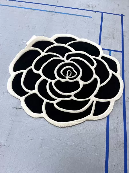 Black flower rug with petals outlined in white.
