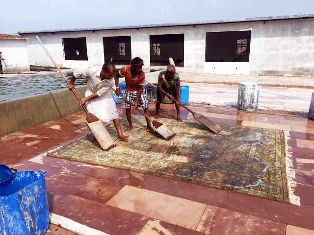Workers wash and squeegie new rug in India.