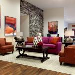 Seating area with neutral rug and red furniture.